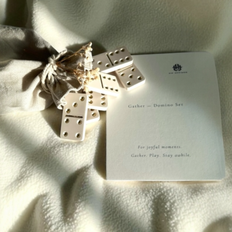 Ensemble de dominos fait main en crème avec des détails dorés, emballé dans un sac en lin.